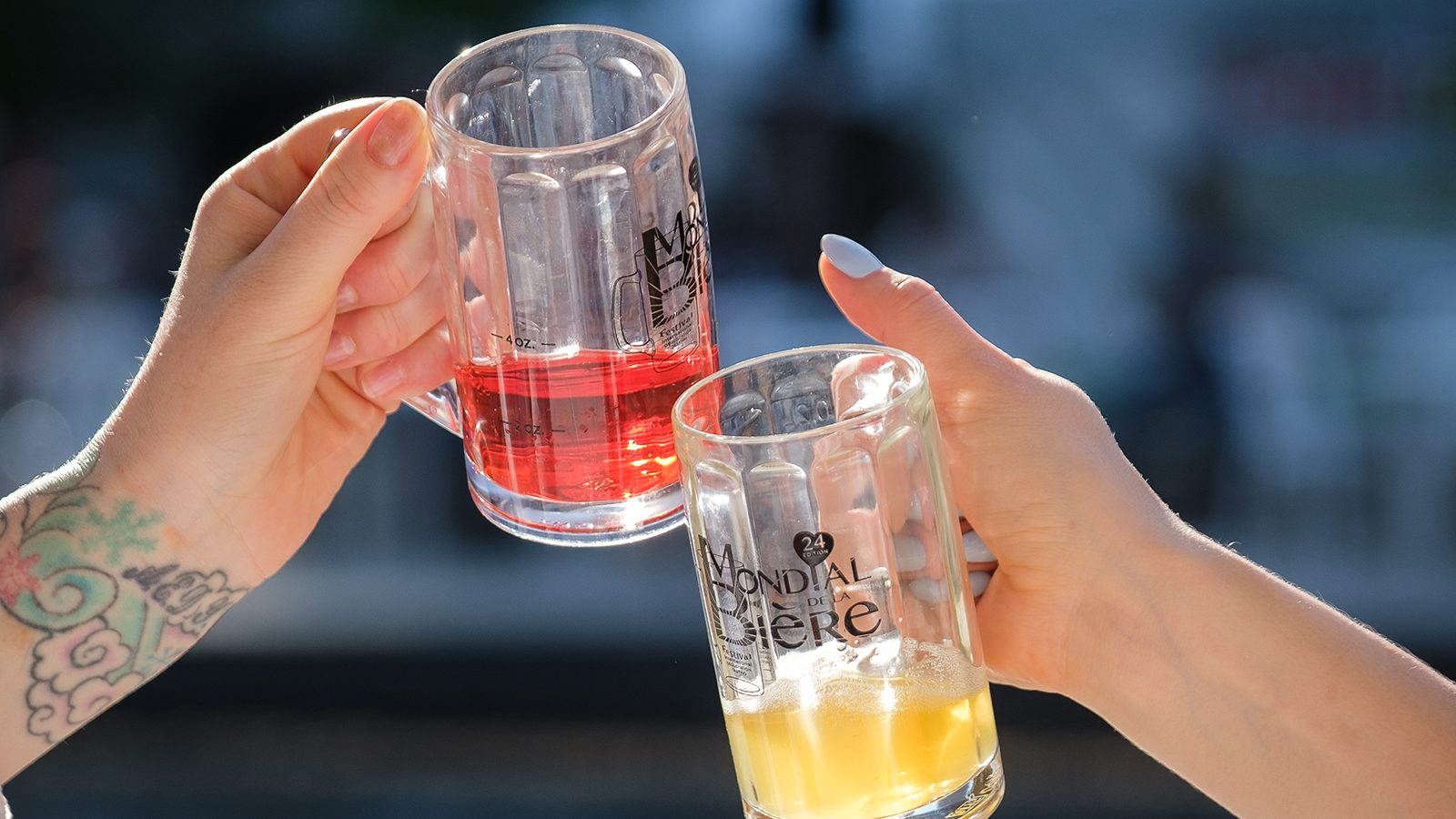 Two individuals cheerfully holding glasses of beer and juice.