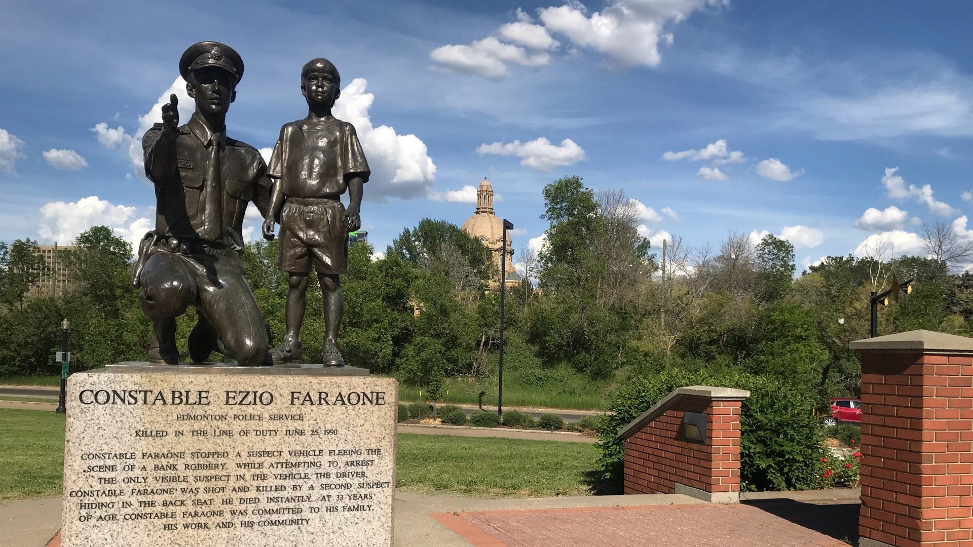 A bronze statue of a kneeling constable beside a young boy, commemorating Constable Ezio Faraone's service and sacrifice.
